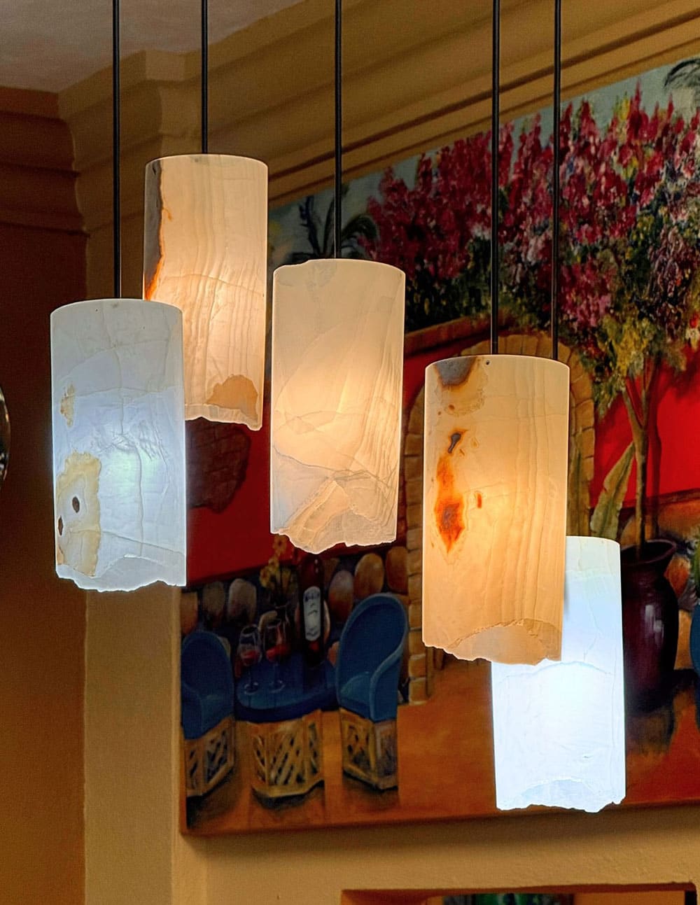 Hand-cut onyx pendant lamps glowing amber above a display of pottery in the showroom