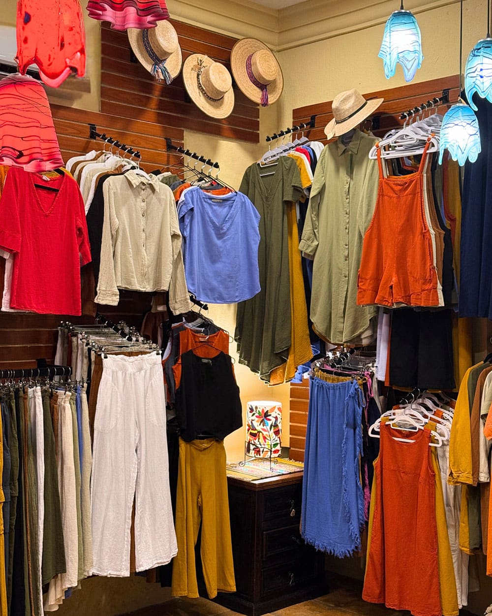 Natural fiber clothing on a rail in the boutique, beside folded textiles and woven bags