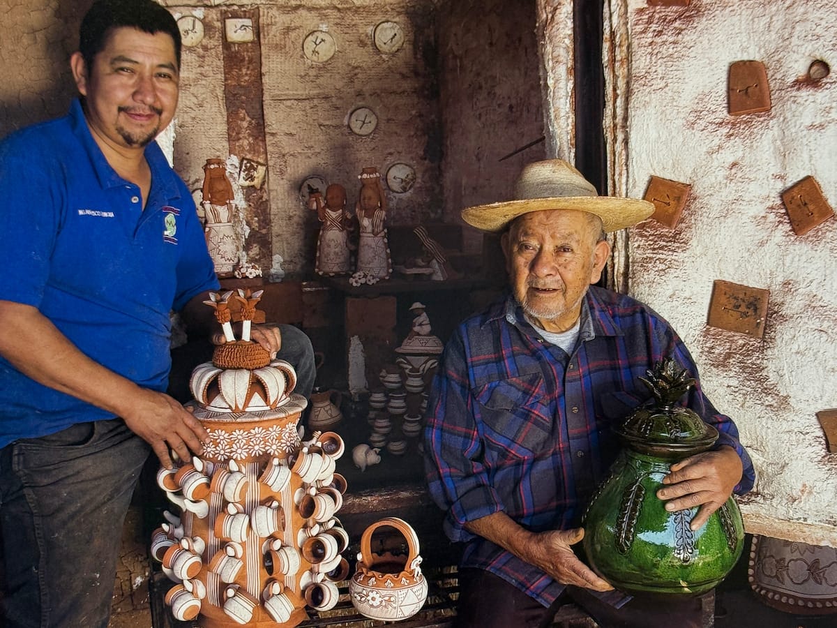 Two Patambán potters in their workshop, holding a tiered piña vessel and a green glazed jar