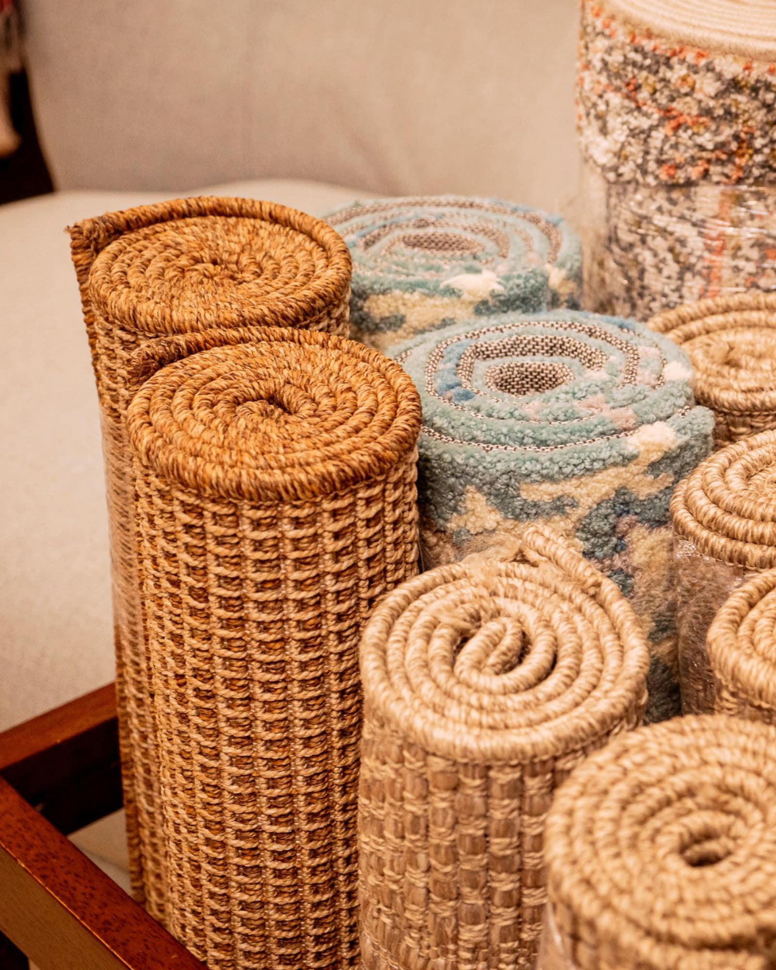 Rolled jute and wool rugs stacked upright, showing woven and tufted textures