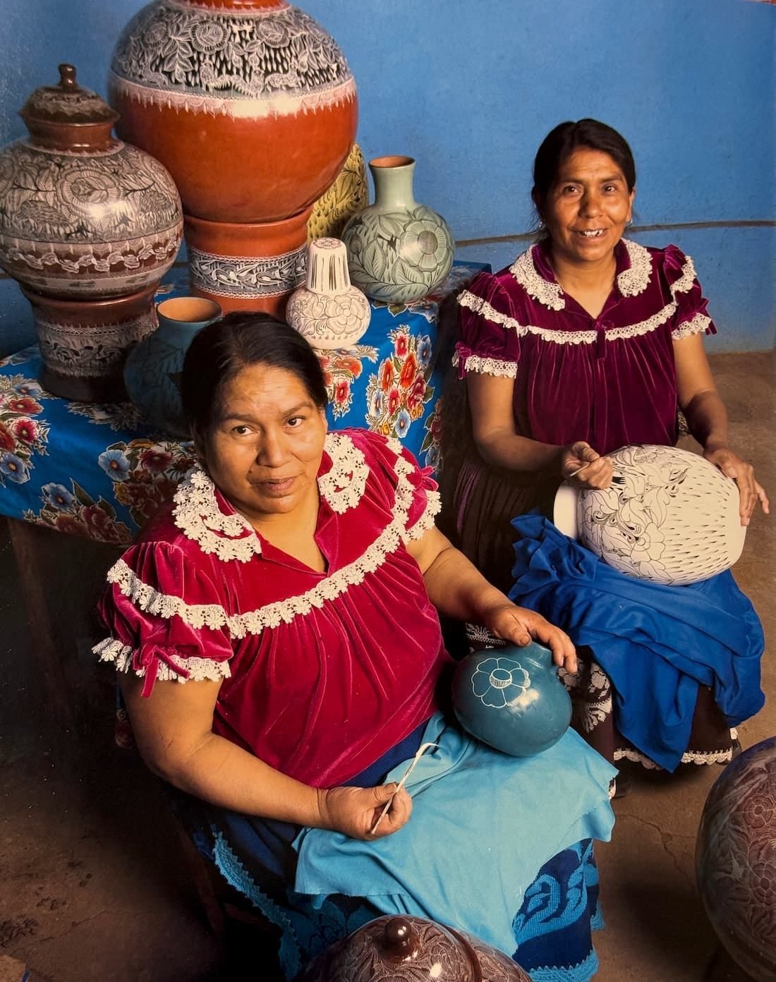 Two Huáncito potters seated with burnished clay vessels and platters
