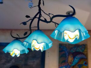 Wrought iron chandelier with three blue, flower-shaped blown glass shades