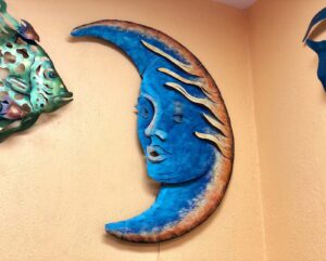 Blue metal wall art piece of a moon with a face