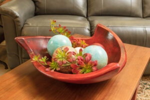 Red decorative ceramic bowl with ceramic spheres and faux florals
