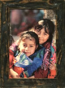 Photograph of two young Mexican girls hugging and smiling
