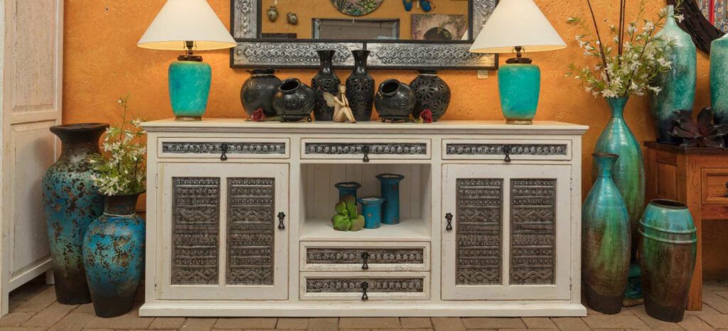 Mexican-made white wooden buffet with metal details, two blue ceramic lamps, and Oaxacan black clay pottery
